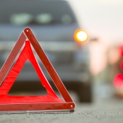 Red emergency triangle stop sign and broken car on a city street